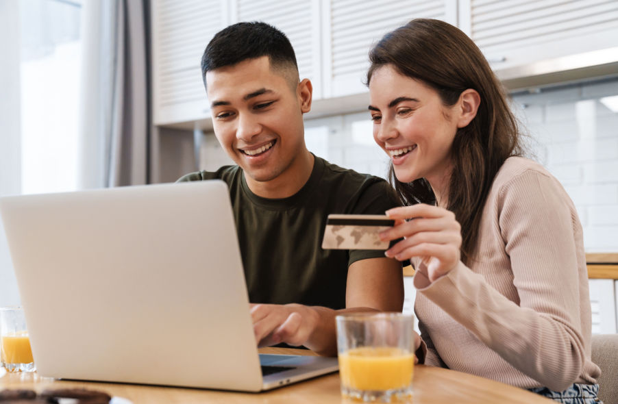 happy couple buying physical gold online using laptop and credit card